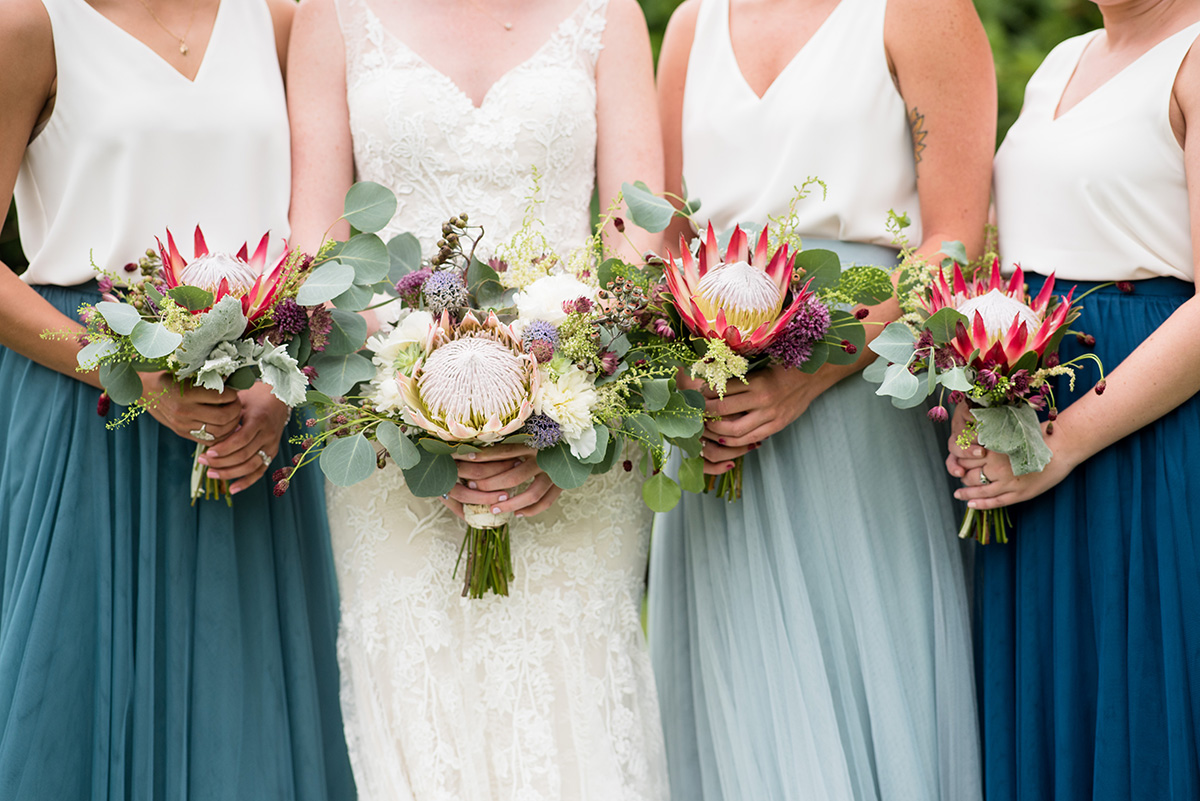 bride and bridesmaids holding boho wedding bouquets featuring protea and succulents