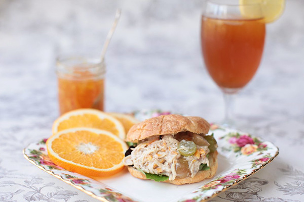 chicken salad sandwich made with a croissant alongside a glass of sweet tea