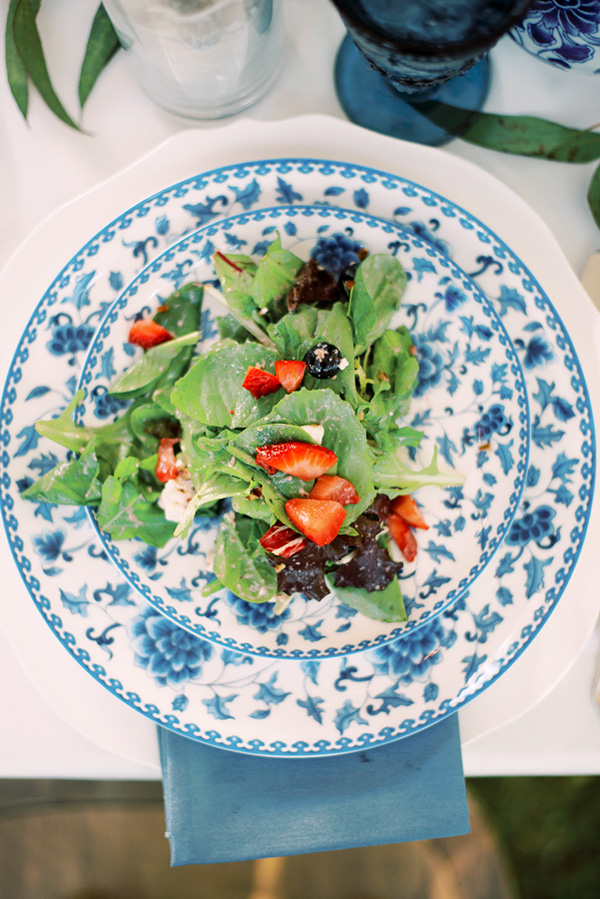 fresh greens and strawberries on blue patterned china