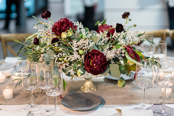 Floral centerpiece with red and white flowers in a mercury glass vessel