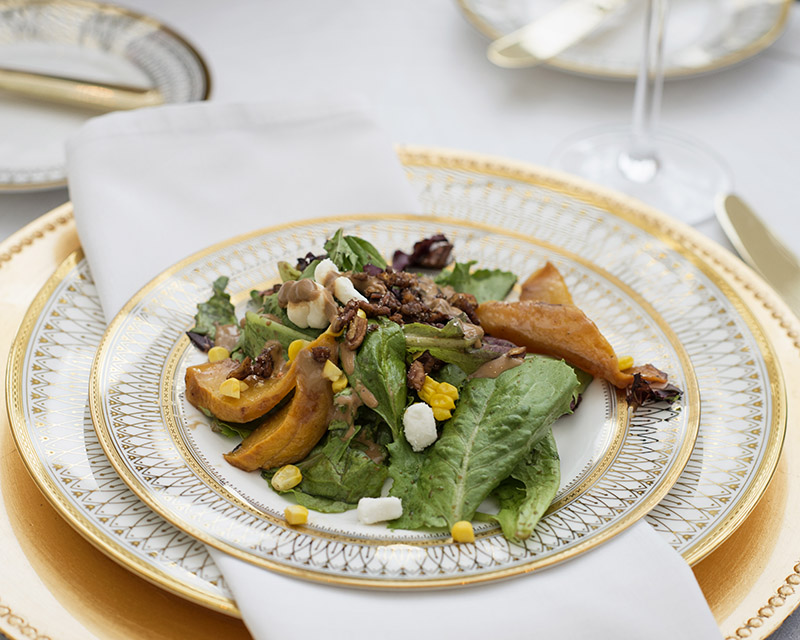 Salad with blue cheese, pecans, and fruit presented on a gold rimmed plate